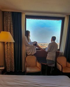 Couple in bathrobes looking at the view from the window of a Panorama Hotel room